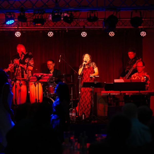 Band performing on stage under red lights.