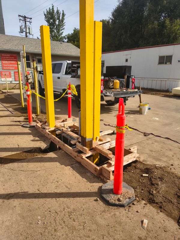 Construction site with yellow posts and traffic cones.