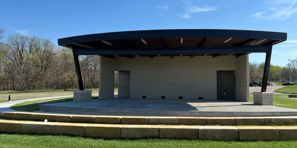 Empty outdoor stage with a curved roof on a sunny day.