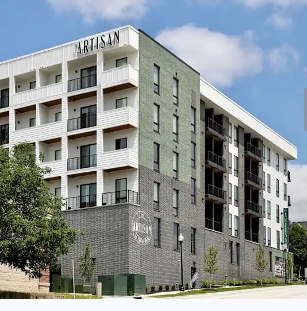 Modern apartment building named Artisan under a blue sky.