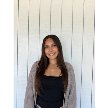 Young woman smiling against a white paneled wall.