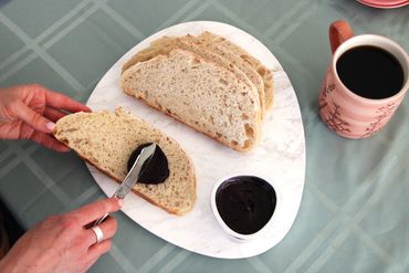Someone spreading jam onto a piece of bread.