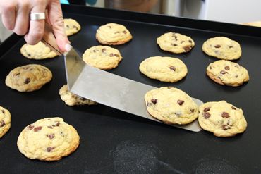 Warm chocolate chip cookies coming off the baking tray.