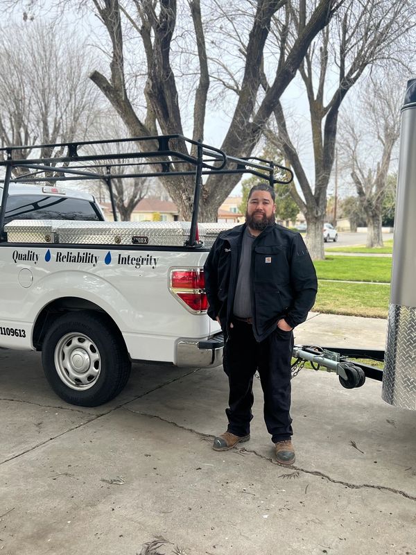 Man standing beside a white pickup truck with quality, reliability, and integrity text.