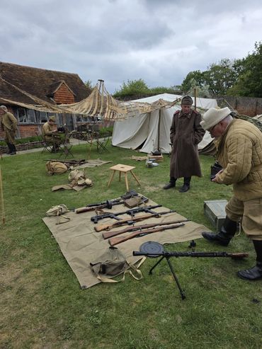 Historical reenactment with vintage rifles and soldiers in period attire at a campsite.