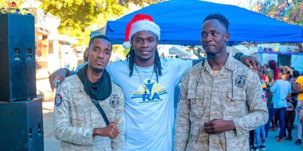 Three men posing, one wearing a Santa hat, with two in camouflage uniforms.