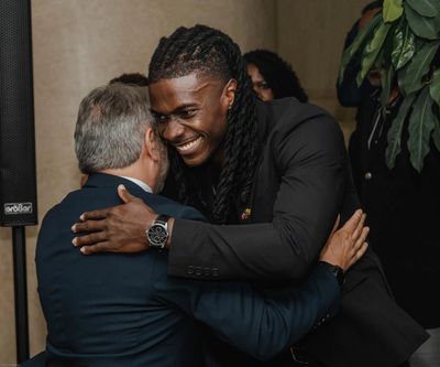 Two men warmly hugging, sharing a joyful moment indoors.
