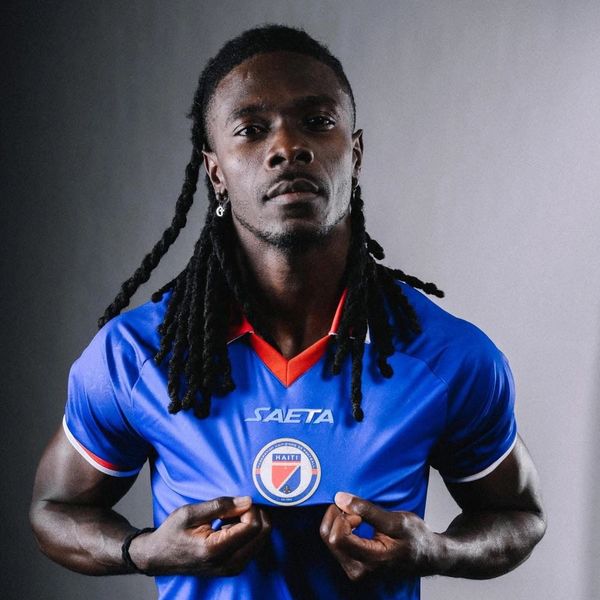 Man with dreadlocks wearing a blue Haiti soccer jersey.