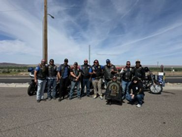 Group of bikers posing with motorcycles on a sunny day.