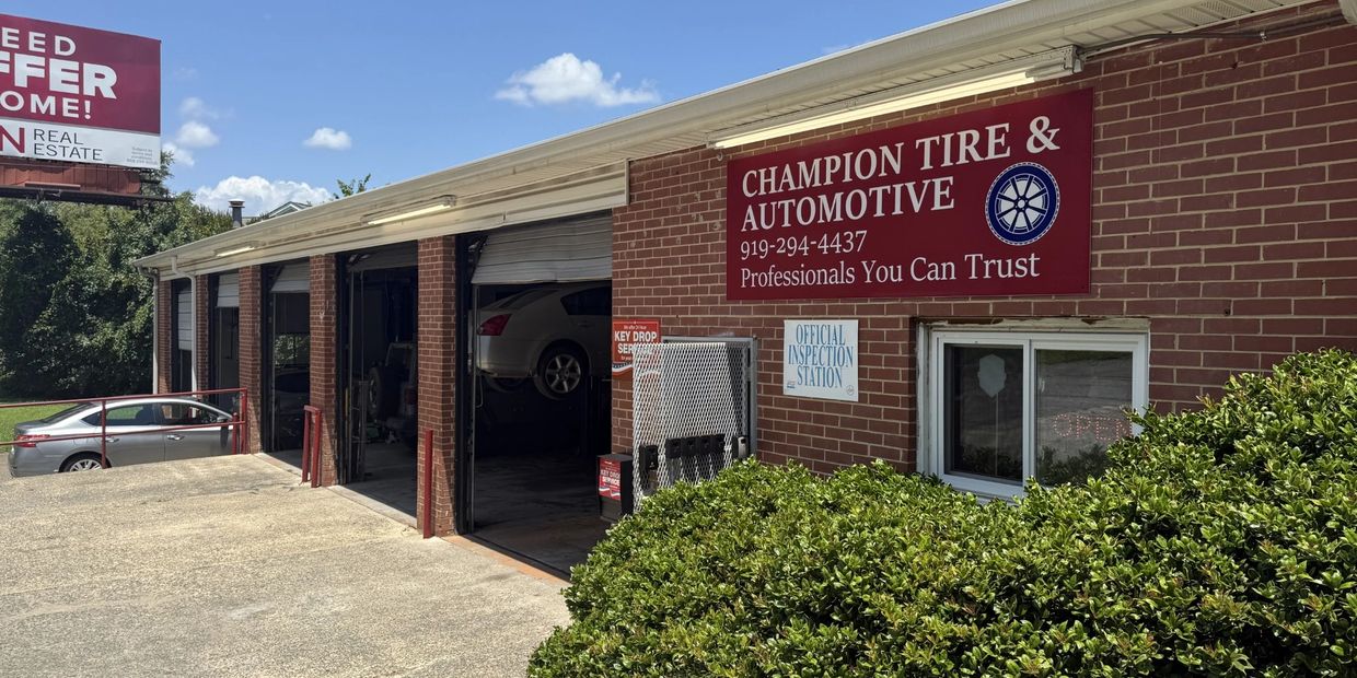 Exterior view of Champion Tire &amp; Automotive garage with cars and signage.
