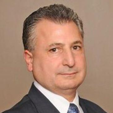 Professional headshot of a middle-aged man in a suit and tie.