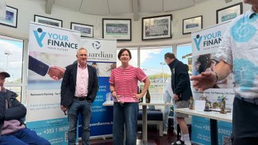 Two people standing near financial banners in a room.