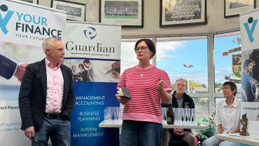 Two people speaking at a finance event with banners in the background.
