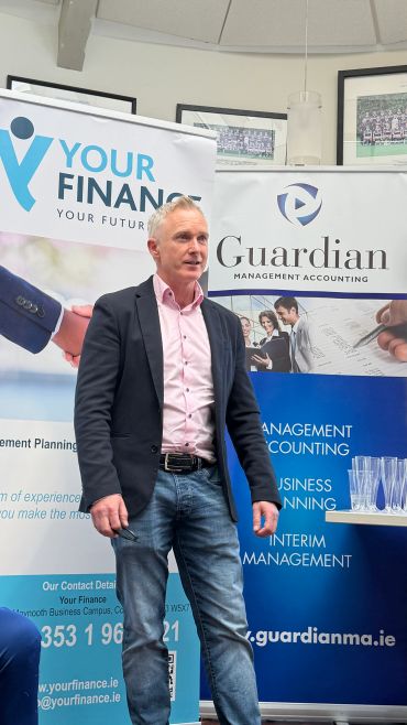 Man in business casual speaking at finance event.