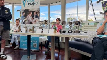 Trophy presentation event with several trophies displayed on a table.