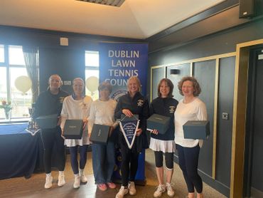 Group of women tennis players holding awards at Dublin Lawn Tennis Council event.