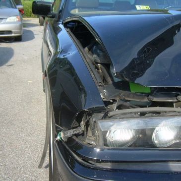 Close-up of a black car with significant front-end damage.