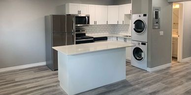 Modern kitchen with island and stacked washer-dryer.
