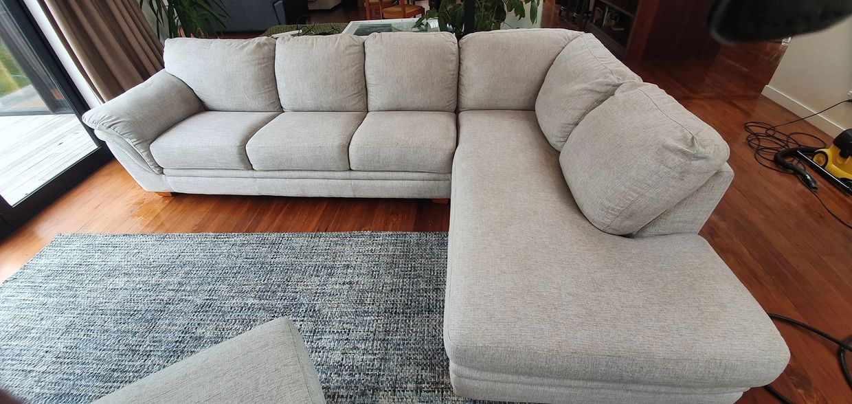 Large L-shaped gray sectional sofa on wooden floor with a blue-gray rug.