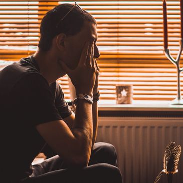 Young male sitting down with hands on face looking like he is upset and needs help and support.