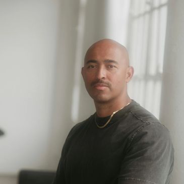 A  young man of mixed origins is looking forward. He looks very thoughtful and calm. 