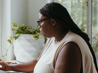 A woman sitting, reflecting in her thoughts and engaging online in her clinical supervision session.