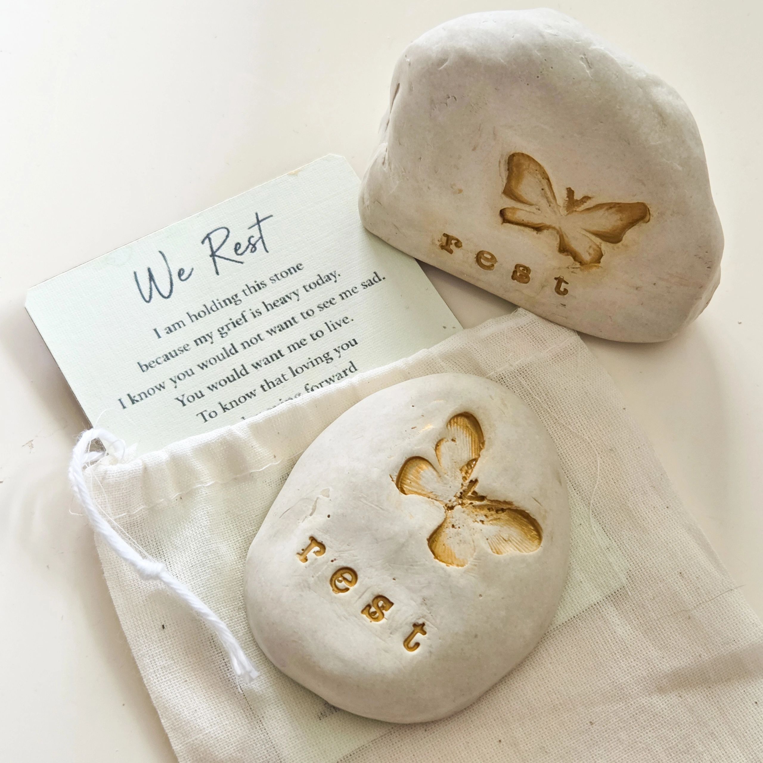 Two stones each with engraved image of butterfly and the word rest in gold color highlight. 