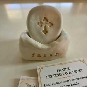 A faith-themed prayer decoration with a cross and prayer cards.