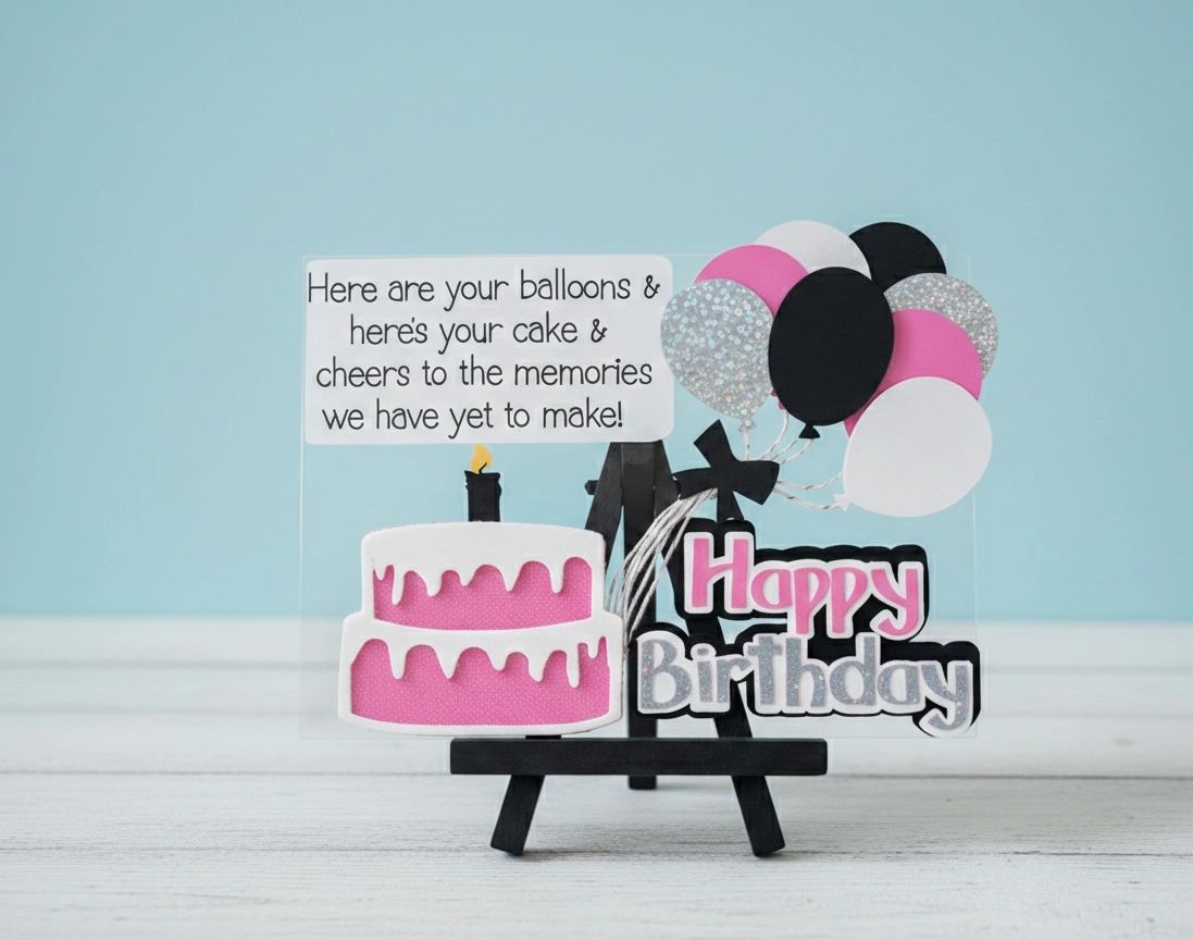 A birthday card with balloons, cake, and a cheerful message on a small easel.