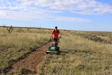 Volunteer mowing sides of trail.