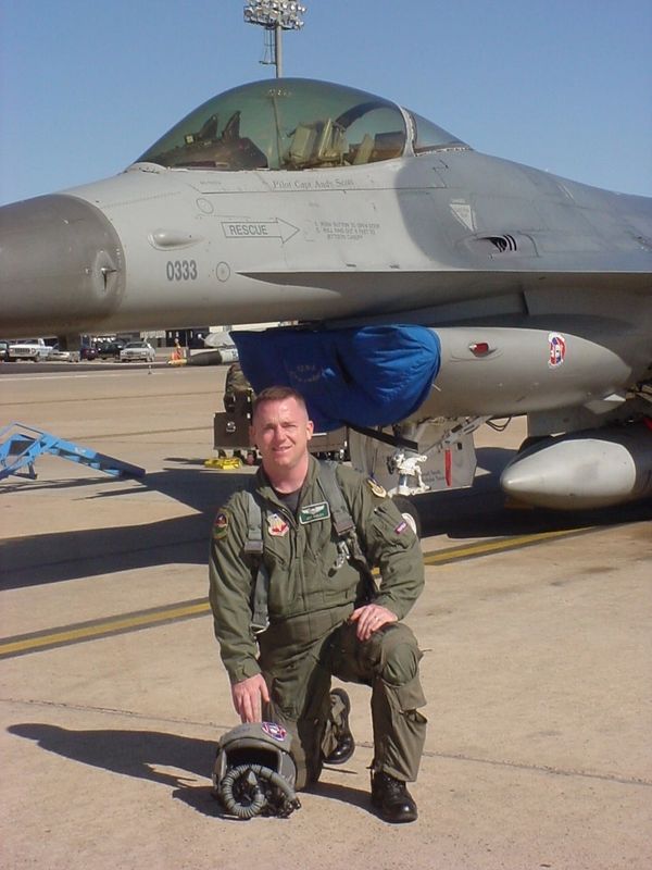 Jeff Pixley kneeling in front of an F-16 fighter jet.