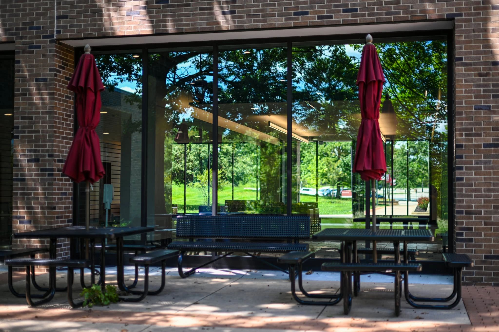Outdoor seating area with red umbrellas and glass reflections.