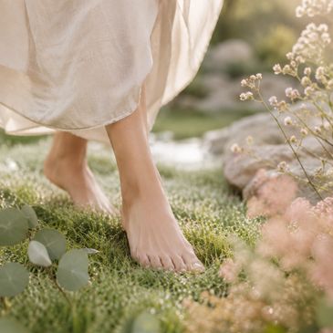 Bare feet walking gently on soft grass surrounded by delicate flowers.