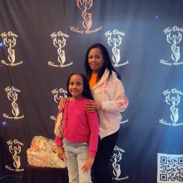 A woman and a girl posing in front of a backdrop with logos.