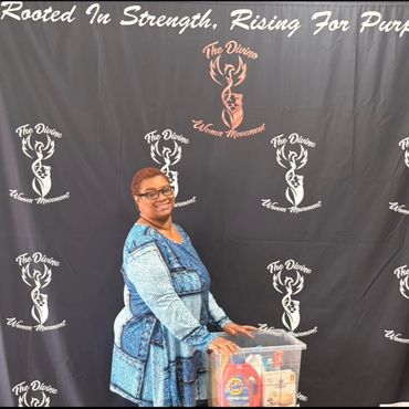 Woman posing in front of a backdrop for The Divine Women Movement.