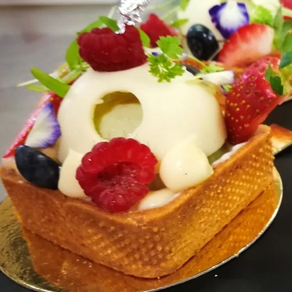 Elegant fruit tart with white chocolate dome and fresh berries.