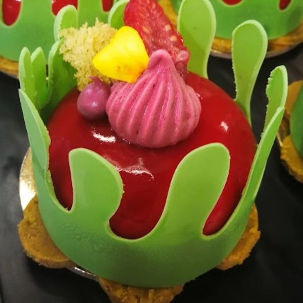 A vibrant red dessert with green chocolate decorations and colorful toppings.