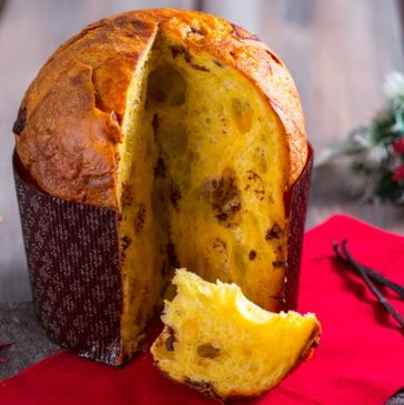 A sliced panettone bread with raisins on a festive table setting.