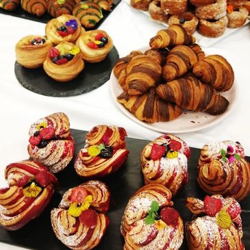 Assorted pastries including fruit-topped danishes and croissants on plates.