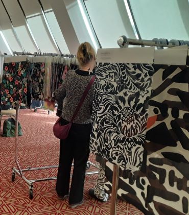 Woman browsing floral fabric on racks indoors.