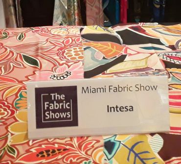 Sign for Intesa at Miami Fabric Show on colorful fabric.