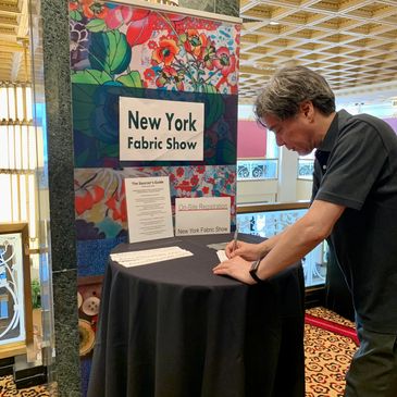 A man writing on a paper at new york fabric show