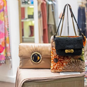Two stylish handbags displayed on a table in a boutique.