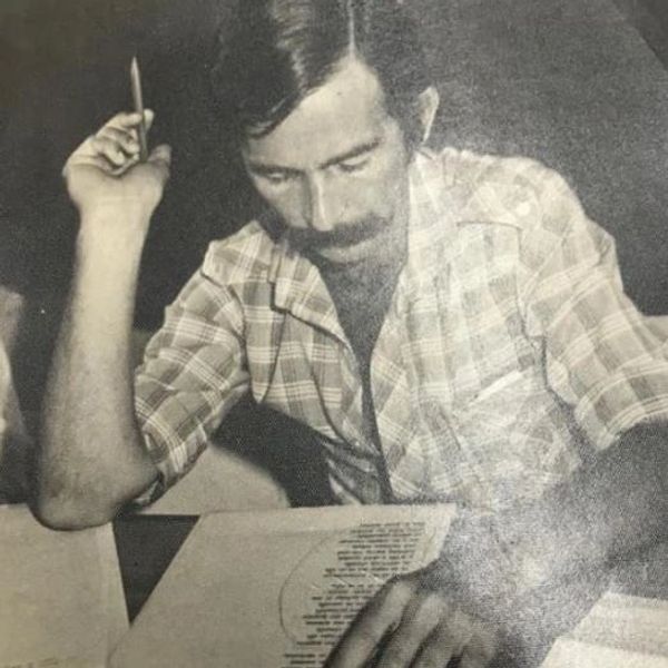 Hombre con camisa a cuadros revisa documentos.