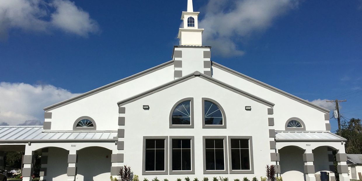 White church building with a steeple under a clear blue sky.