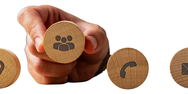 Hand holding a wooden block with a group icon among other communication icons.