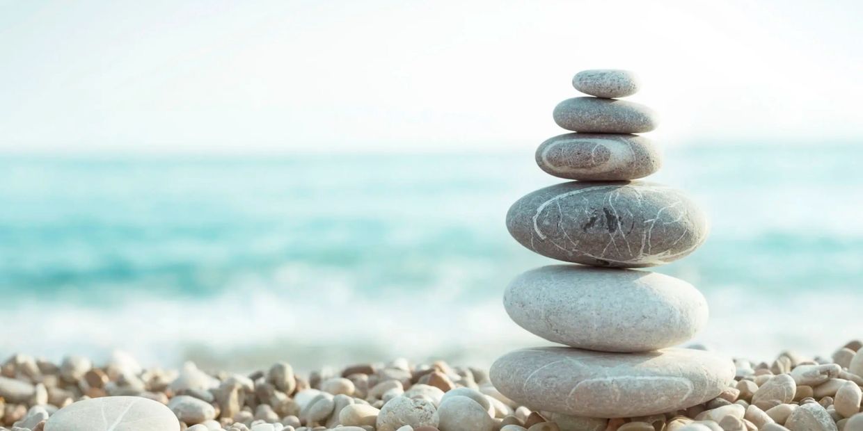 Balanced stack of smooth stones on a pebble beach by the sea.