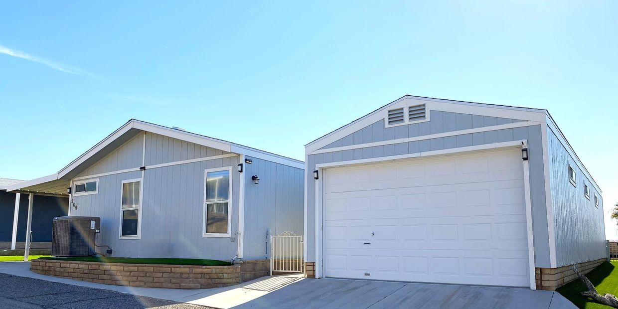 Modern gray house with white trim and a large garage under a clear blue sky.