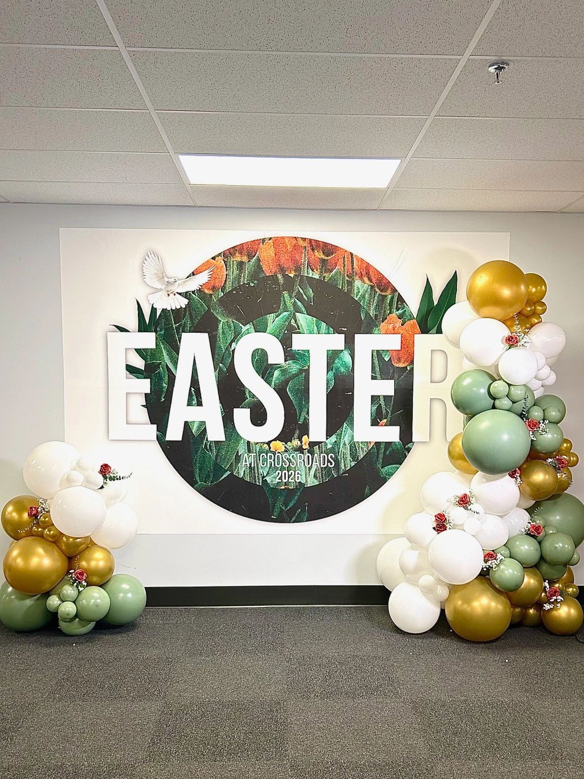 Easter celebration backdrop with floral and balloon decorations.