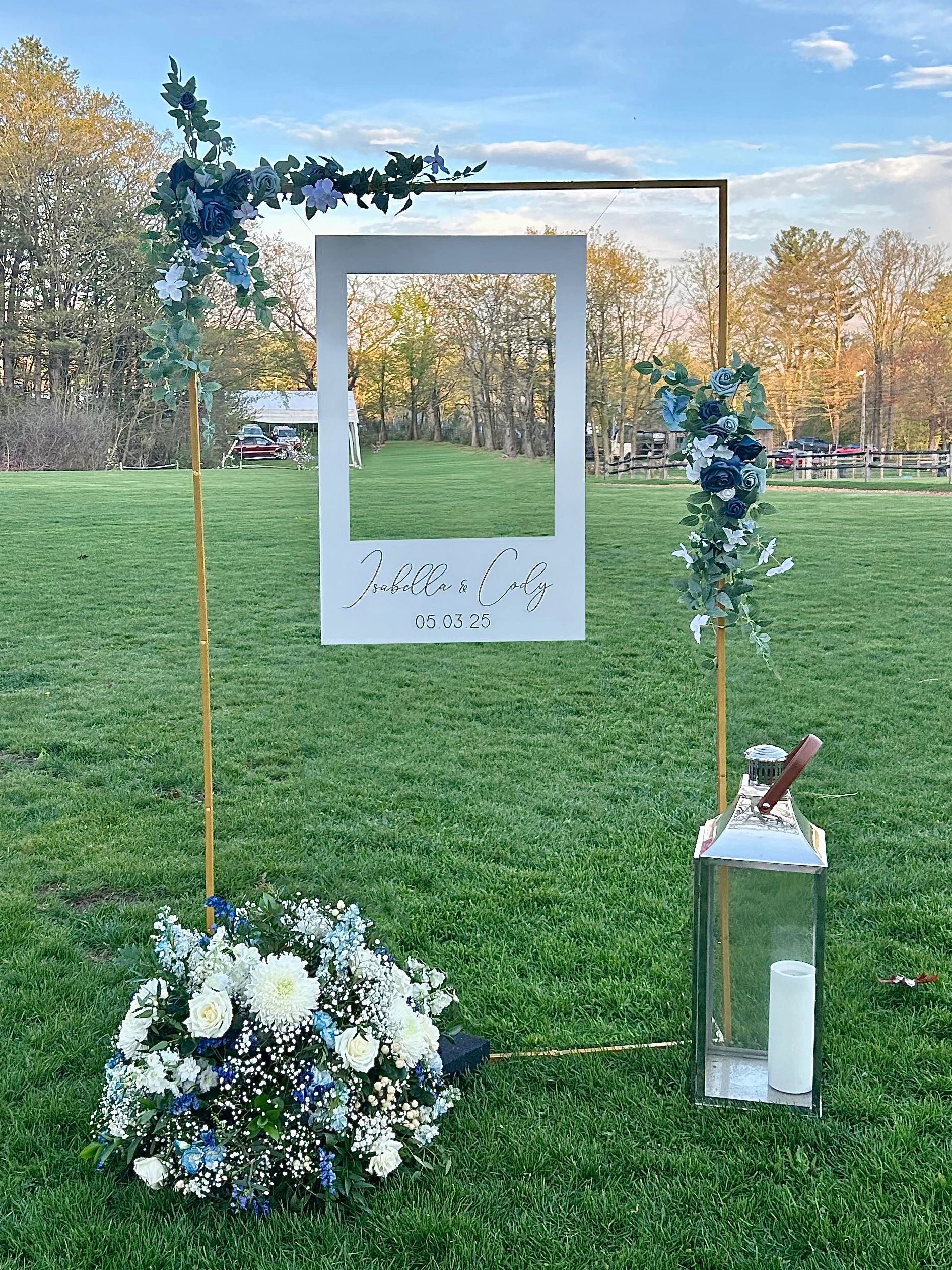 A wedding photo frame with floral decorations on a green lawn.